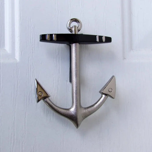 Metallic anchor-shaped door knocker on a white wooden door