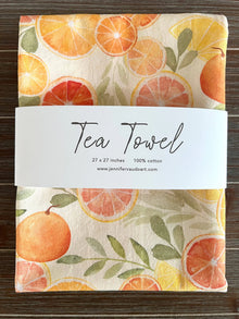 A cream-colored handmade tea towel with watercolor citrus slices perfect for any citrus lover kitchen decor