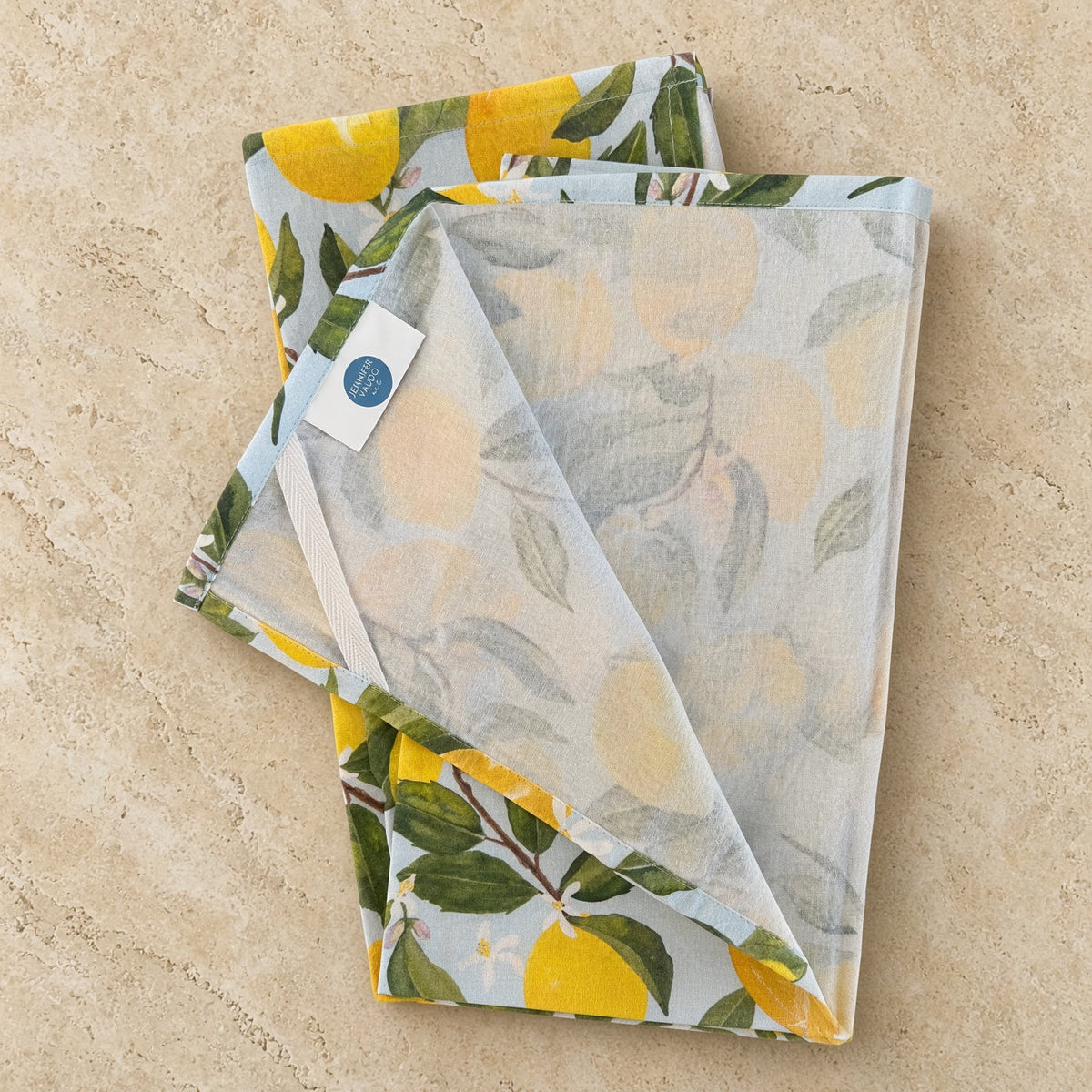 Artisan tea towel with pre-washed flour sack linen featuring watercolor lemons and delicate blossoms on blue background