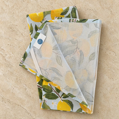 Artisan tea towel with pre-washed flour sack linen featuring watercolor lemons and delicate blossoms on blue background