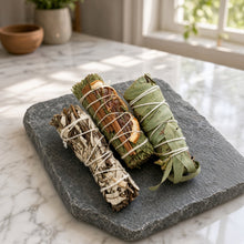 Three aromatic smudge sticks with dried herbs and cinnamon bark bound in white twine for meditation practice gift trio