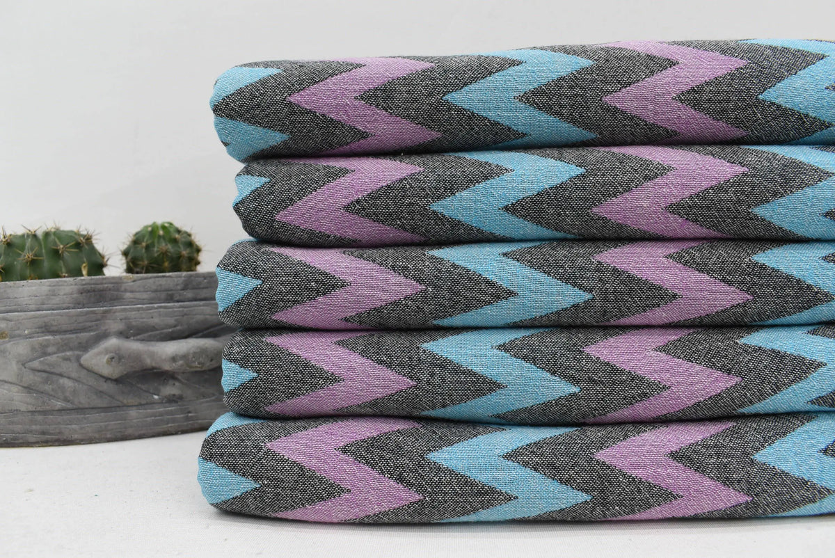 Stack of folded organic bath towels with bold teal lavender and charcoal zigzag pattern perfect for beach use