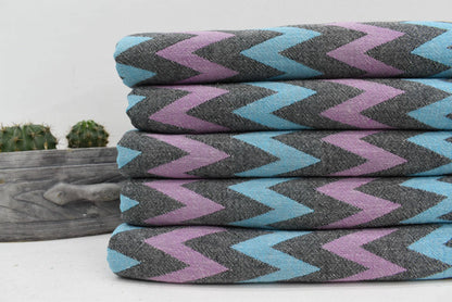 Stack of folded organic bath towels with bold teal lavender and charcoal zigzag pattern perfect for beach use