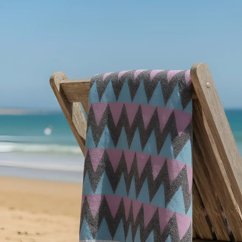 Authentic turkish organic cotton beach towel with bold blue fuchsia and gray zigzag pattern draped on lounge chair