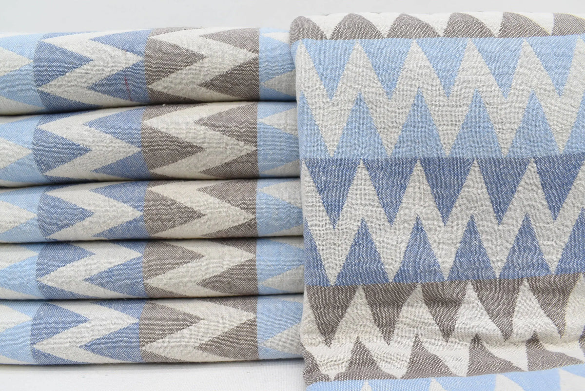 Stacked rolls of light blue and gray zigzag patterned organic turkish cotton towels 36x78 for beach use