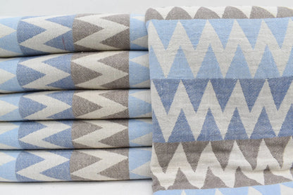 Stacked rolls of light blue and gray zigzag patterned organic turkish cotton towels 36x78 for beach use