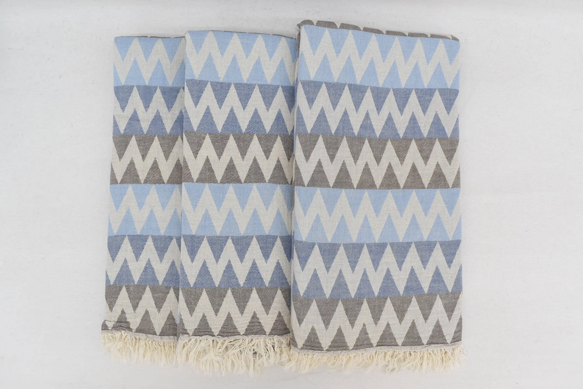 A soft organic turkish towel with light blue gray zigzag pattern and natural fringe perfect as a beach towel