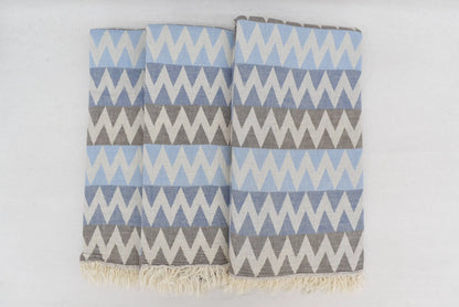 A soft organic turkish towel with light blue gray zigzag pattern and natural fringe perfect as a beach towel