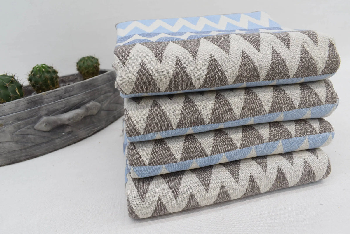 Stack of folded organic turkish towels with gray white and light blue zigzag pattern beach towel 36x78