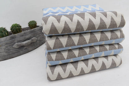 Stack of folded organic turkish towels with gray white and light blue zigzag pattern beach towel 36x78