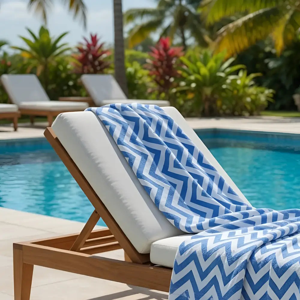 Blue and white chevron patterned authentic turkish organic cotton beach towel draped over wooden lounge chair by pool