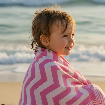 A child wrapped in an authentic turkish organic cotton beach towel with pink and white zigzag pattern