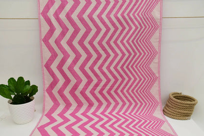 A vibrant pink and white zigzag pattern peshtemal towel with a soft textured weave perfect for beach or bath use