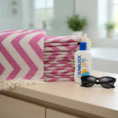 Stack of authentic turkish organic cotton beach towels in pink and cream chevron pattern with fringed edges