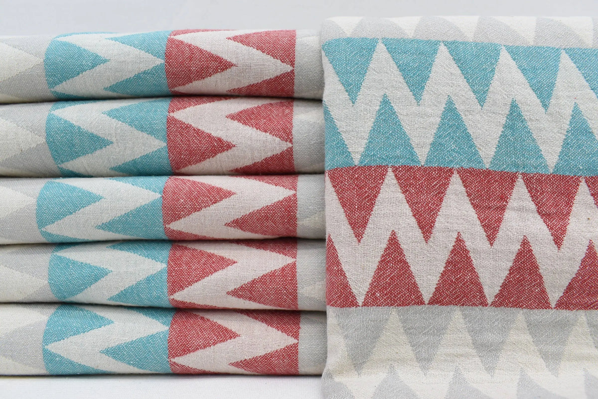 Stacked organic turkish towels with teal coral pink and white zigzag pattern perfect beach towel choice