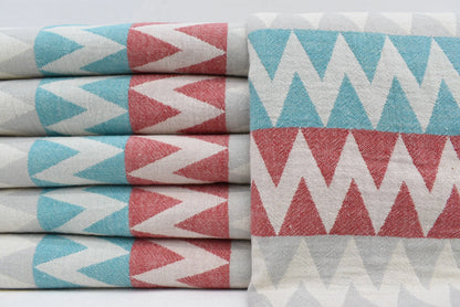 Stacked organic turkish towels with teal coral pink and white zigzag pattern perfect beach towel choice