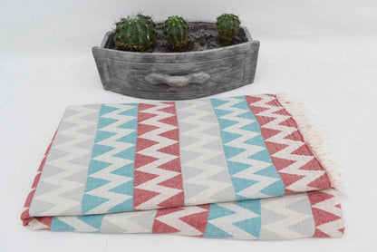 Folded organic turkish towel beach towel with bold red teal and gray zigzag stripes and soft fringed edges