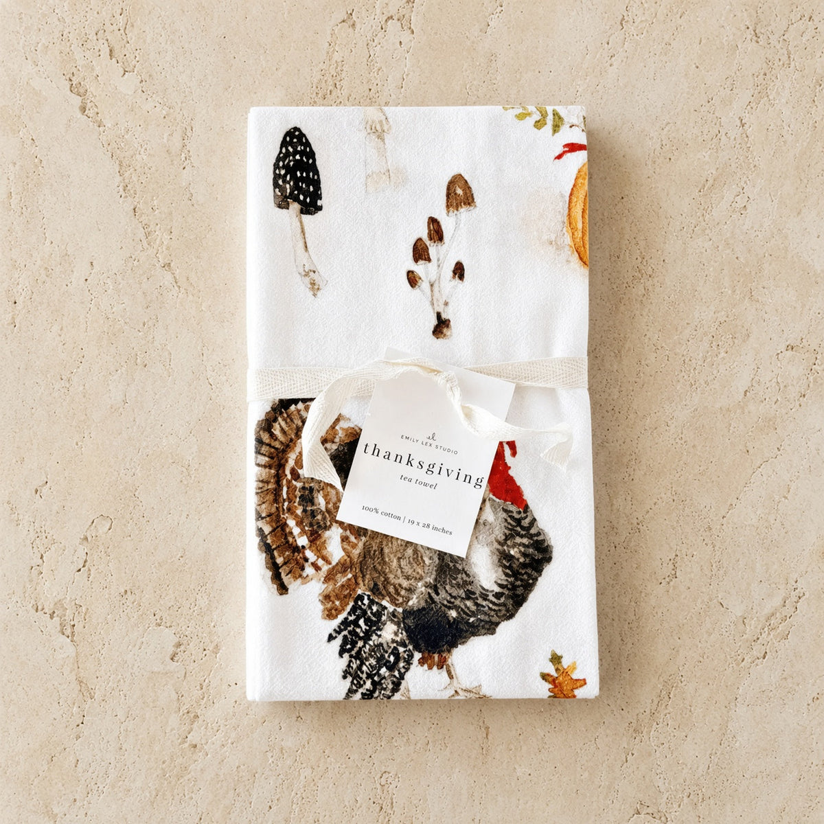 White thanksgiving tea towel with detailed turkey mushrooms autumn leaves paired with african zulu trivet nest