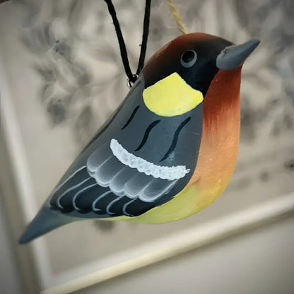 Colorful bird-shaped ornament hanging against a neutral background