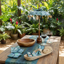 Balinese tabletop umbrella blue and green floral with teal gold pattern tassels and wooden pole inspired by ornamental parasols on a tropical lanai with plants
