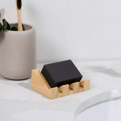 A sleek black soap on a bamboo soap lift with a mountain-shaped design crafted to show nature’s rugged beauty