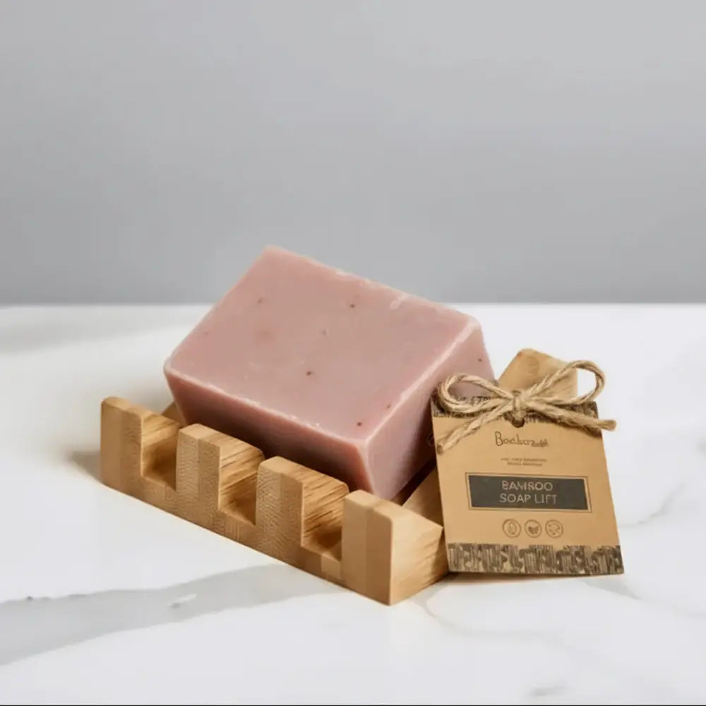 A pale pink soap bar on a bamboo soap lift with a mountain-shaped design crafted to showcase natures rugged beauty