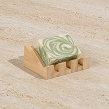 A light green and white swirled soap bar on a bamboo soap lift with mountain-shaped design crafted to showcase nature’s rugged beauty