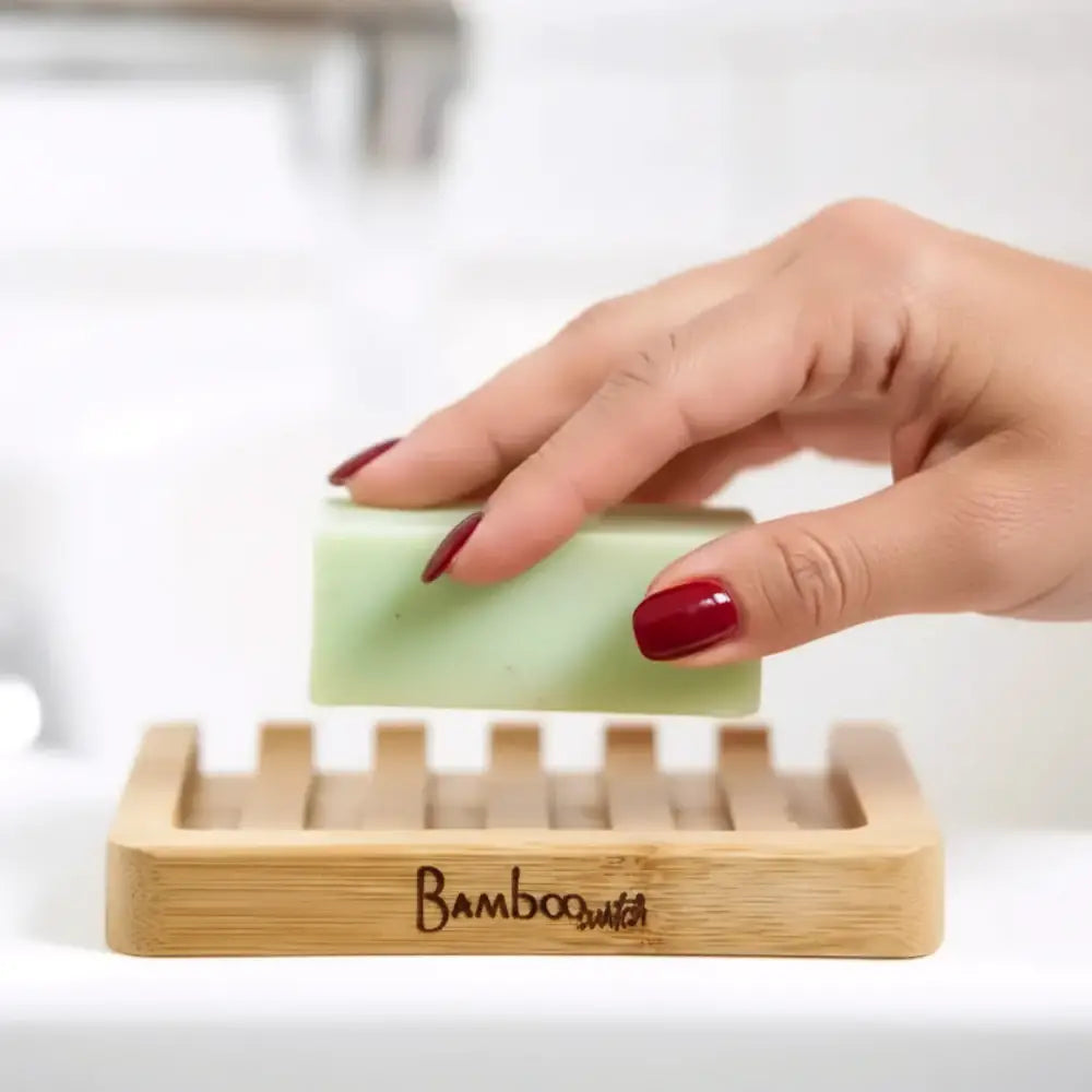 A pale green soap held above a bamboo soap lift with a lattice design that allows drainage and airflow
