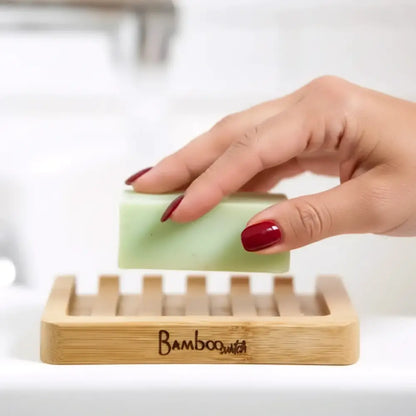 A pale green soap held above a bamboo soap lift with a lattice design that allows drainage and airflow