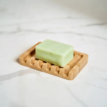 Light green bar soap rests on a bamboo soap lift with a lattice design that allows drainage and airflow
