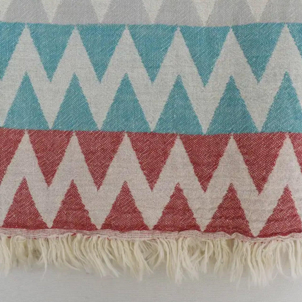 A woven organic turkish towel beach towel with teal coral cream zigzag pattern and soft fringed edges