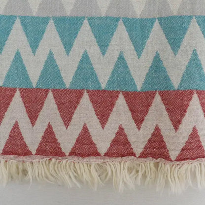 A woven organic turkish towel beach towel with teal coral cream zigzag pattern and soft fringed edges