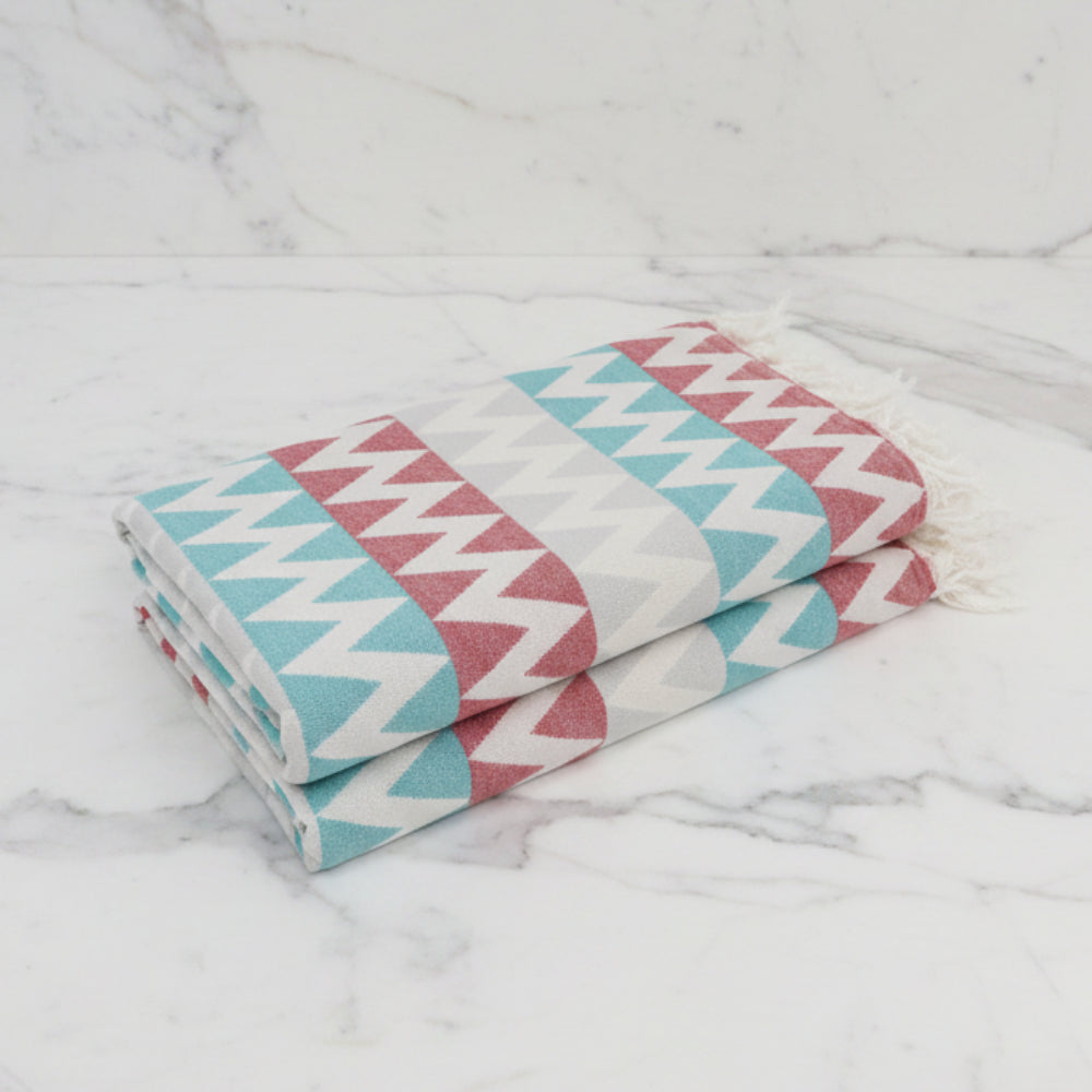 Folded organic turkish towel beach towel with bold red teal and gray zigzag stripes and soft fringed edges