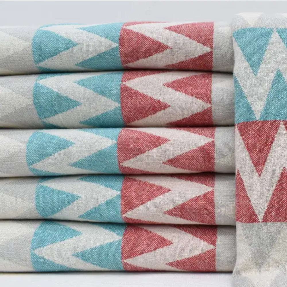 Stacked organic turkish towels with teal coral pink and white zigzag pattern perfect beach towel choice