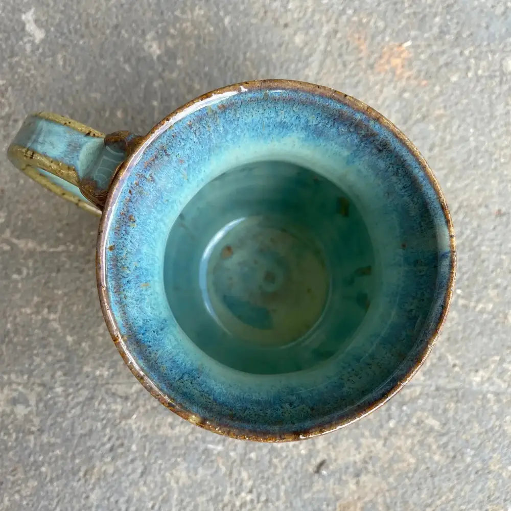 This handmade pottery mug features a warm mustard honeycomb base with an adorable bee design and sea foam blue rim. 
