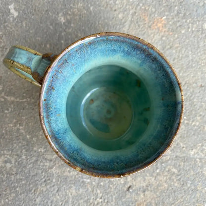 This handmade pottery mug features a warm mustard honeycomb base with an adorable bee design and sea foam blue rim. 