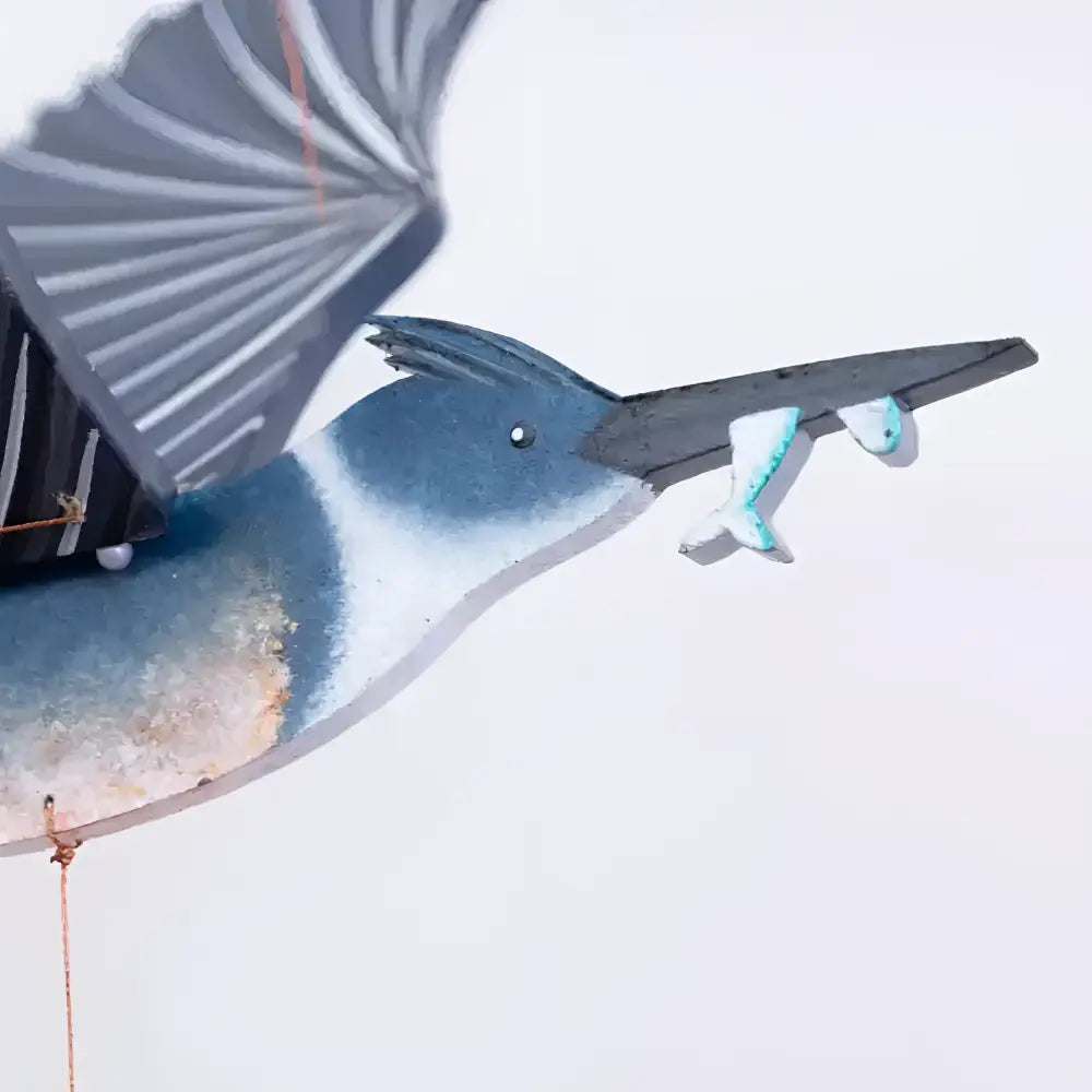 Blue and white painted wooden belted kingfisher flying bird mobile with black beak holding two small fish
