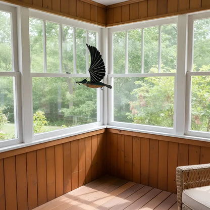 Black and brown metal belted kingfisher flying bird mobile hanging in a sunlit room as a flying bird mobile decor