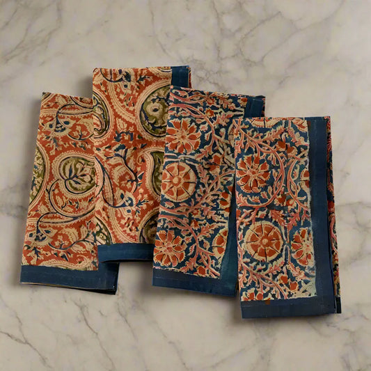Four folded Block Print Compass Paisley Napkins with floral and paisley patterns and teal borders