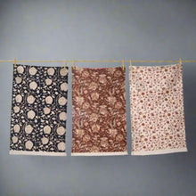 Colorful block print tea towels with floral patterns hanging on a line for a cozy kitchen look