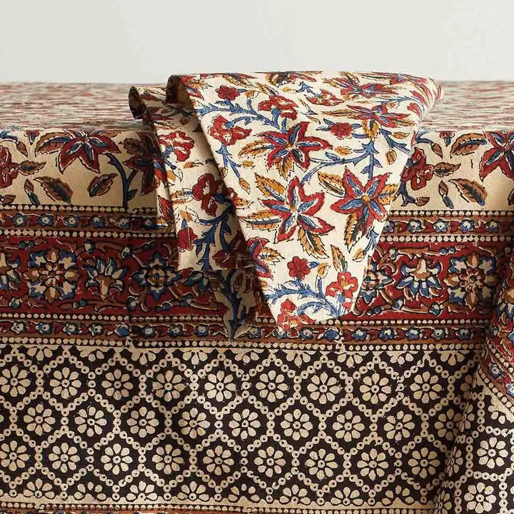 Rust and black multicolor printed tablecloth on table with a napkin.