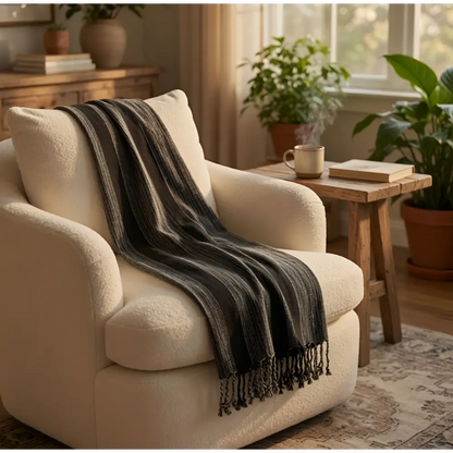 Cream-colored plush armchair draped with bold stripes turkish towels dark gray handwoven striped towel