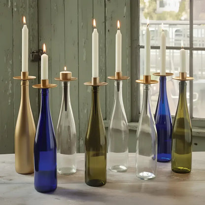 A set of seven glass bottles with brass bottelabra™ taper holders and white taper candles transforms bottles into decor