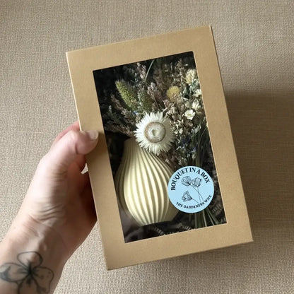 Cream-colored ribbed ceramic vase holding a dried floral bouquet from boyds custom fabrication gift set