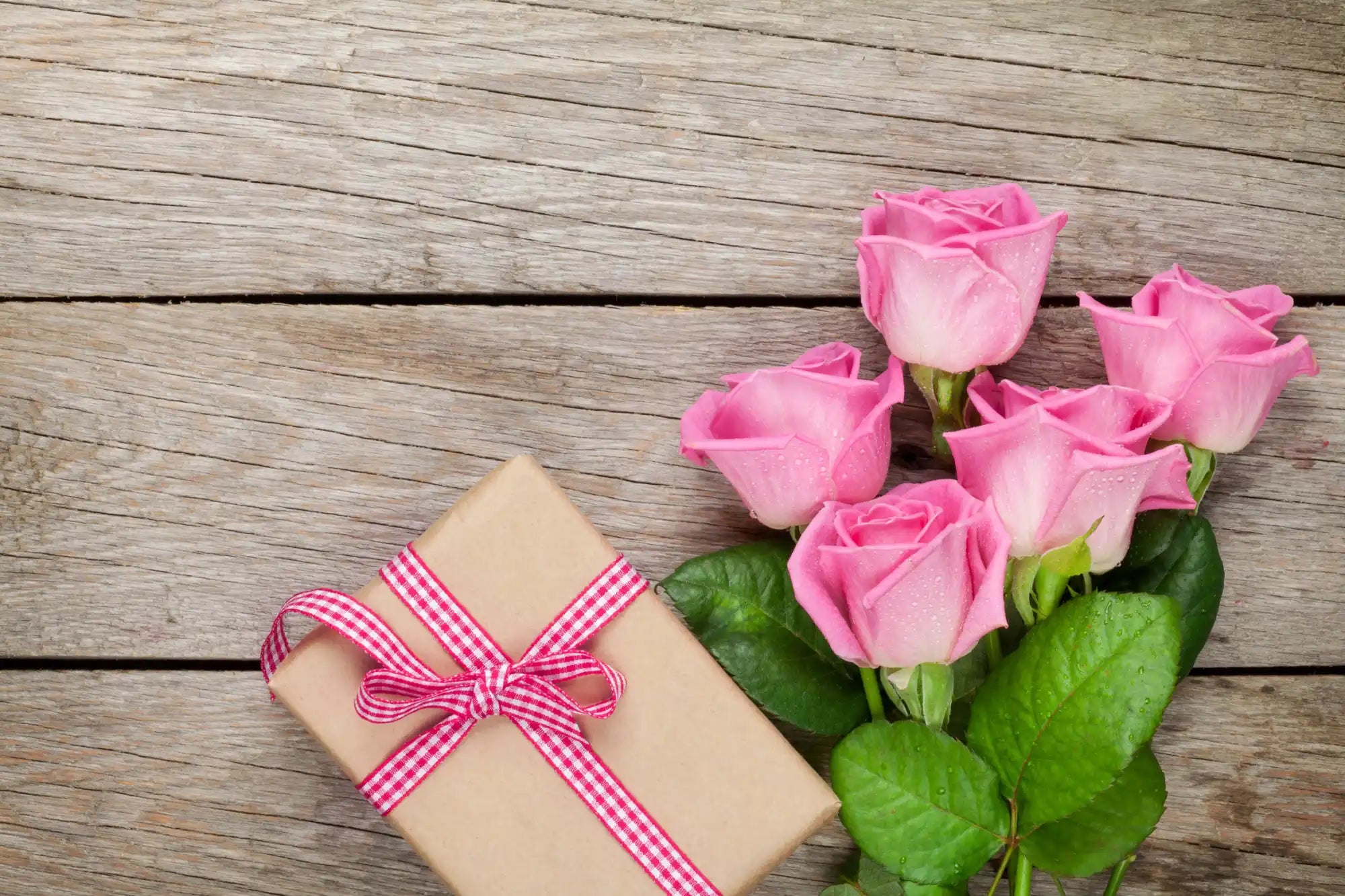 A bouquet of pink roses and a gift box with a pink ribbon.