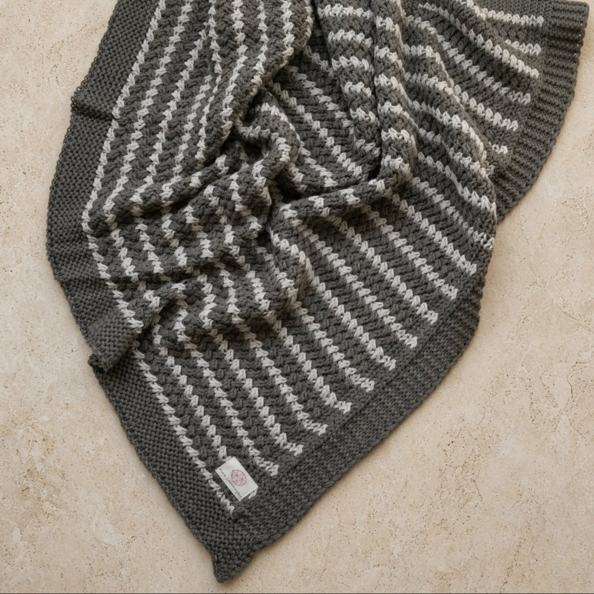 A cozy organic cotton throw with natural zigzag knit and soft gray off-white stripes perfect for chunky-knit beauty lovers