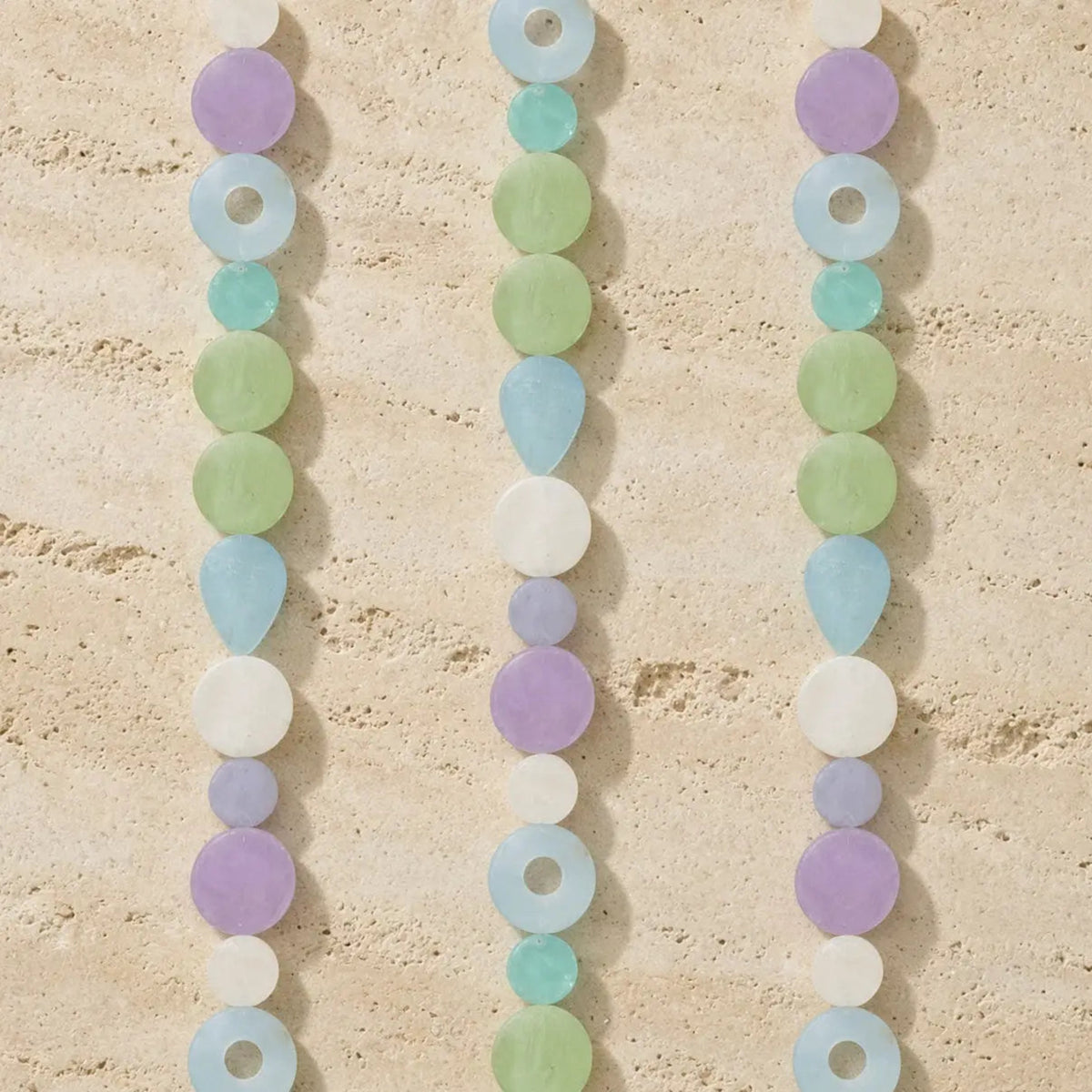 Pastel-colored capiz strand watch light dance with iridescent shells in lavender, mint green, light blue, and white beads
