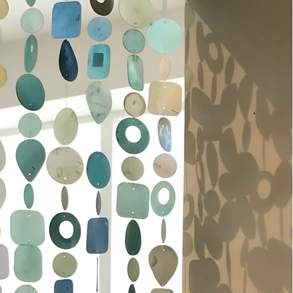 A handmade eco-friendly capiz strand curtain with translucent hand-cut glass pieces in teal blue and green shades