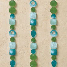Three vertical strands of capiz glass beads in teal blue and green watch light dance on decorative strands