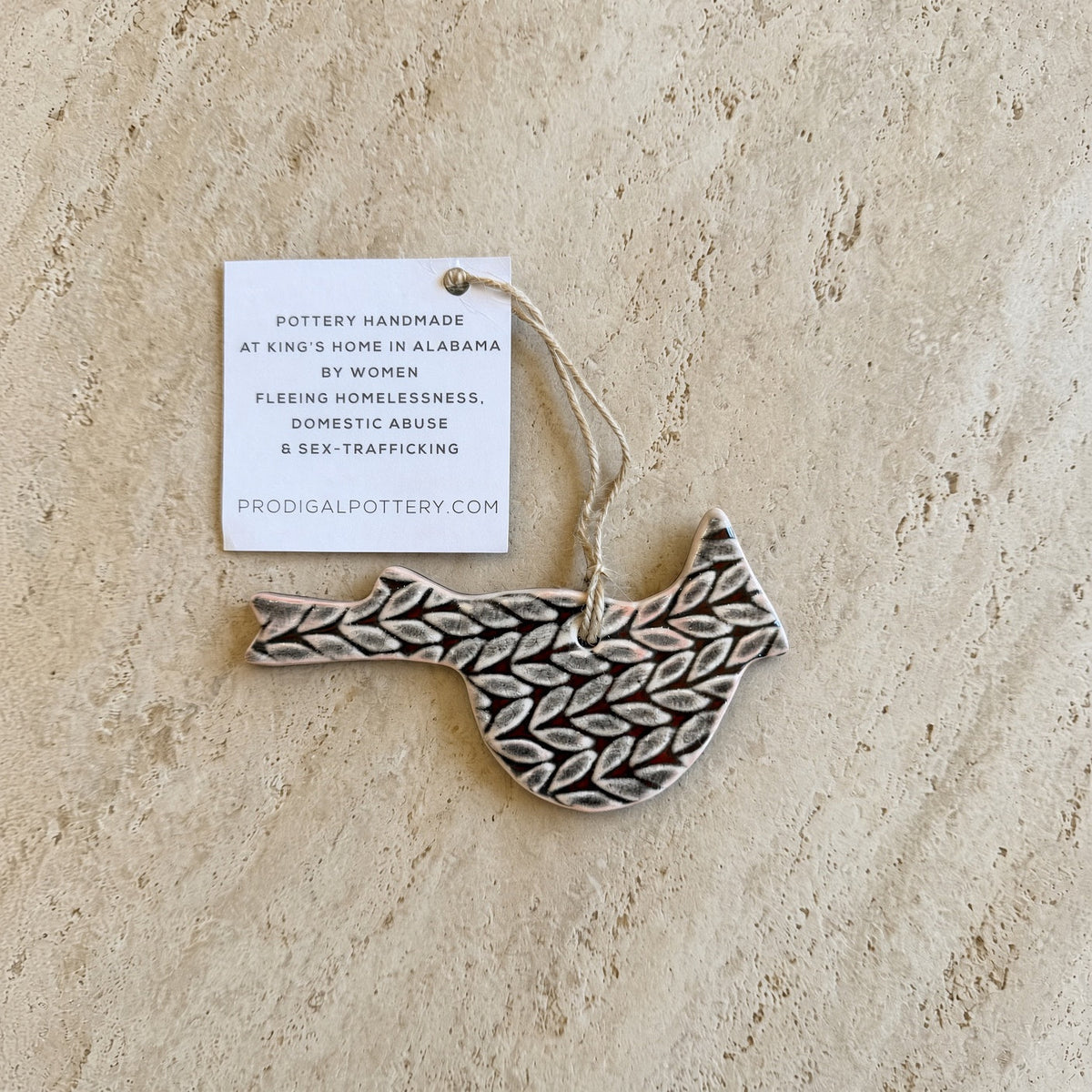 A ceramic cardinal ornament with a beautifully imprinted leaf-patterned surface in earthy tones perfect for holiday décor